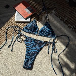 Flat lay of zebra print bikini with blue and black patterns and gold metal buckle accents