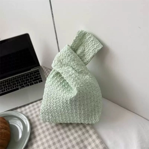 Japanese style light green pleated wrist bag on a table for casual outing and daily use