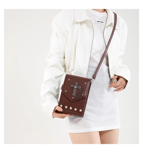 Detail view of dark brown y2k crossbody bag with vintage metal cross and silver star rivets