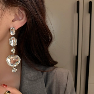 Close-up of dangling rhinestone heart earrings with oversized crystals on model