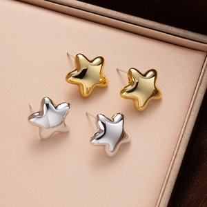 Polished gold and silver star stud earrings presented in a luxury jewelry box