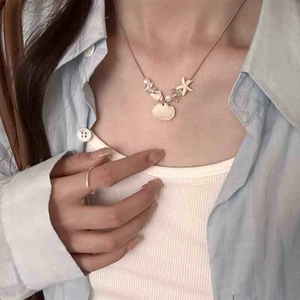 Detailed view of ocean style starfish and shell pendant necklace on female model