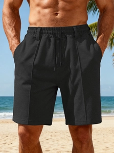 Men's black waffle knit shorts with drawstring waist on a sunny beach landscape