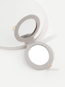 Close-up of a grey round foldable PU leather pocket mirror with gold metal accents