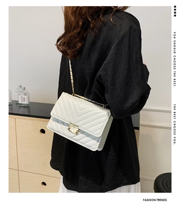 Detail of white chevron quilted crossbody bag with golden chain strap and metal lock