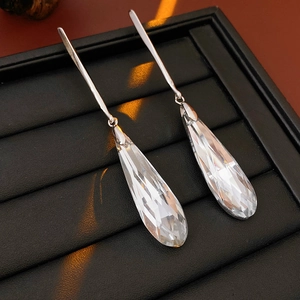 Macro shot of faceted clear crystal teardrop earrings on a black leather tray