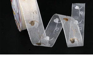 Close-up of white organza ribbon with gold foil heart pattern for gift wrapping