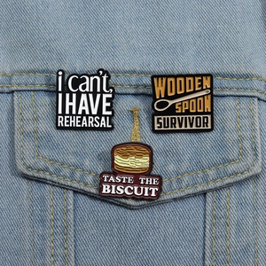 Three novelty enamel pins including a wooden spoon and burger design on a denim jacket