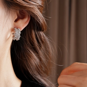 Close-up of a silver C-shaped stud earring with micro-pave cubic zirconia on model