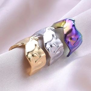 Detailed close-up of irregular liquid metal rings in gold, silver and iridescent finishes