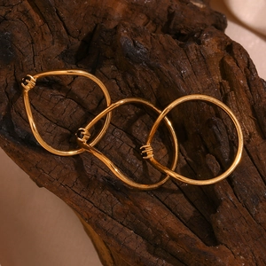 Detailed view of three interlinked 18K gold plated V-shaped rings on rustic wood