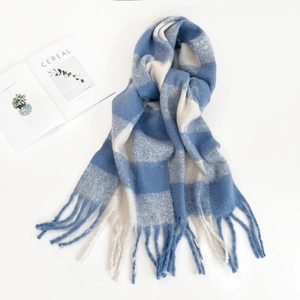 Detail shot of a blue and white checkered mohair scarf with soft fringes next to a book