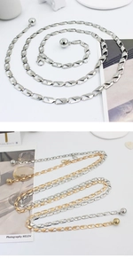 Detail view of gold and silver metal waist chains with lobster clasps and ball pendants