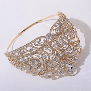 Detailed close-up of golden crown with teardrop crystal and intricate wave rhinestones