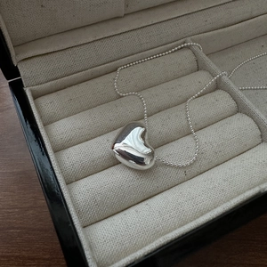 Minimalist S925 sterling silver heart pendant necklace on a premium beige jewelry box liner