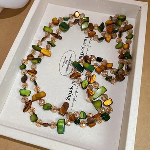 Detail of irregular colorful shell petals and champagne crystal beads on a long necklace