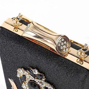 Detail van zwarte glitter avondtas met goudkleurig montuur en met juwelen bezette sluiting