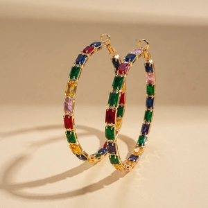 Detail of large gold hoop earrings set with colorful rectangular rainbow crystals
