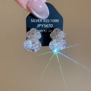 Détail macro de boucles d'oreilles trèfle en argent 925 avec grands zircons ovales