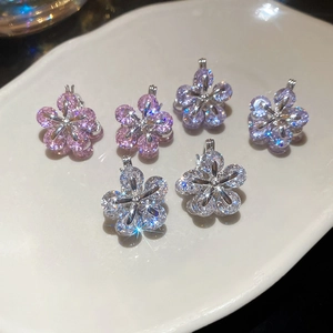 Close-up of zircon flower charms in purple and white on a white decorative tray