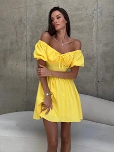 Detail eines gelben Off-Shoulder-Kleides mit Puffärmeln und einer Schleife am Ausschnitt
