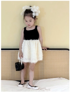 Detail of girls black vest dress with white faux fur skirt and pearl handbag accessory