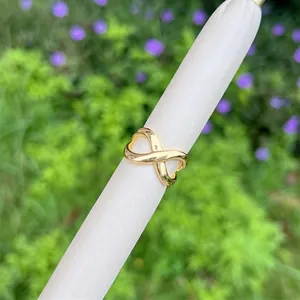 Detailed view of an infinity-shaped 18K gold-plated adjustable ring on a display stand