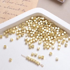 Macro shot of 14k gold plated cube spacer beads on white tray for jewelry making