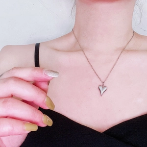 Close-up of a minimalist silver heart pendant necklace worn on a woman's collarbone