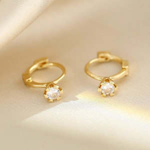 Macro view of 18K gold earrings with round clear zircon stones on gold silk