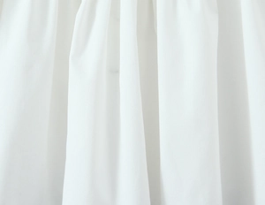 Detailed macro view of white embroidered fabric texture and pleated material finish