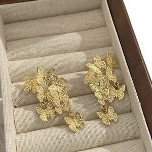 Macro detail of golden butterfly drop earrings on soft velvet jewelry box