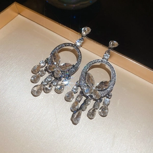Macro shot of silver butterfly hoop earrings with sparkling crystal tassels on gold tray