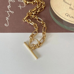 Close-up of golden chunky chain necklace featuring a classic OT toggle clasp design