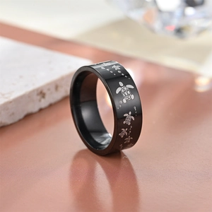Macro shot of black stainless steel ring featuring detailed laser-engraved turtle patterns