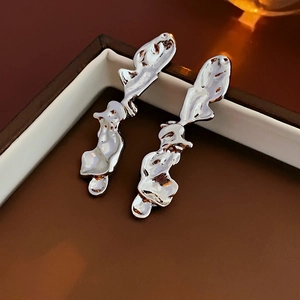 Detail of liquid metal style silver earrings with irregular fluid design on a box