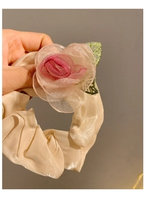 Detailed view of beige satin scrunchie with large pink organza flower hair accessory