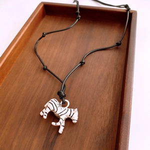 Artistic zebra pendant necklace with white enamel on an adjustable black woven rope