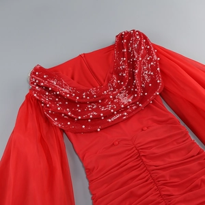 Gros plan d'une robe rouge montrant des paillettes, des perles et un tissu froncé