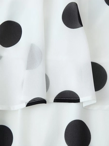 Detailaufnahme von weißem Chiffonstoff mit schwarzen Punkten und feiner Nahtverarbeitung