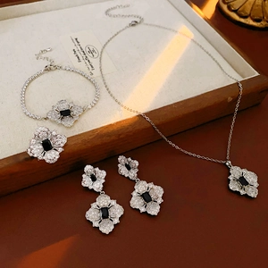 Detailed view of silver flower jewelry set with black stones and zircon pavé inlay