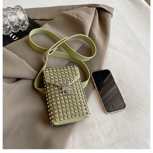 Detail of sage green crossbody bag with rhinestones, metal twist lock, and wide strap
