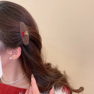 Detail of plush brown triangle hair clip with red cherry and gold bow on model