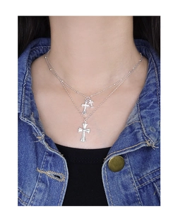 Close-up of double layer silver cross necklace worn on a blue denim jacket