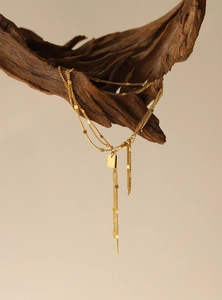 Detail of 18K gold-plated multi-layer fringe bracelet hanging on natural wood branch