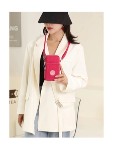 Detail view of pink nylon crossbody phone bag with multi-layer zippers on a model