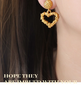 Detailed close-up of gold heart earrings with twisted hollow wire design on model