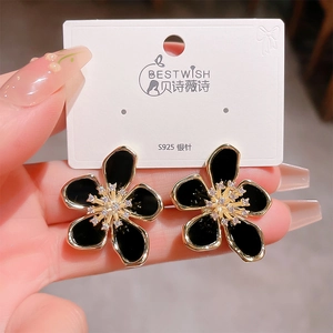 Detail of five-petal black enamel flower earring with gold edges and zircon center