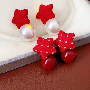 Close-up of fabric star earrings with red polka dots and faux pearls for women