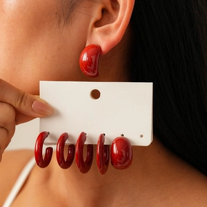 Close-up of geometric red acrylic earrings in teardrop and C-shape styles for women